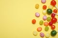 Many different hard candies on yellow background, flat lay. Space for text