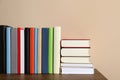 Many different hardcover books on wooden table near beige wall. Space for text