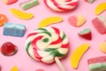 Many different jelly candies and lollipop on pink background, closeup