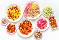 Many different jelly candies on plates on a white
