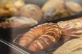 Many different pastries lie behind a glass window of a bakery shop