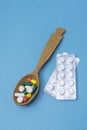 Many different pills and capsules of medicines in wooden spoon on blue background. Copy space, selective focus. The concept of Royalty Free Stock Photo