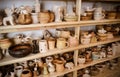 Many different pottery standing on the shelves in a pottery workshop. Low light