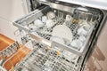 Many of dirty dishes in the dishwasher. Built-in dishwashers with opened door. Home appliance dishwasher machine in Royalty Free Stock Photo