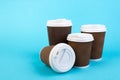 Many disposable paper cups of coffee, tea on blue background.