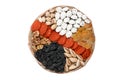 Many dried fruits on a round wooden plate, cashew nuts, prunes, figs, raisin and apricots isolated on white Royalty Free Stock Photo