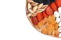 Many dried fruits on a round wooden plate, cashew nuts, prunes, figs, raisin and apricots isolated on white Royalty Free Stock Photo