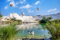 Many ducks are in the water at Travertines of Pamukkale or thermal pools and hot air balloons float in the sky Royalty Free Stock Photo