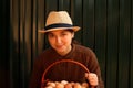 Many eggs in basket. Young woman in hat holding whole basket of brown organic eggs on modern green background. Poultry