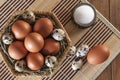 Many eggs. Large brown chicken eggs and small motley quail eggs on straw in wicker basket and salt in salt shaker on wooden table