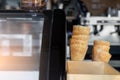 Many empty baked waffle cones and paper cups for ice cream stacked at display counter window of street food takeaway Royalty Free Stock Photo