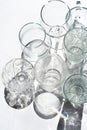 Many empty crystal wine, coctail glasses on white. Transparent beverage cups silhouette on sunlight, rainbow reflection