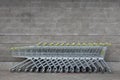 Many empty shopping trolleys with yellow handle standing in a row in the centre of photo at gray brick background of