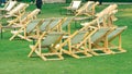 Many empty white deck chairs with tables in lawn is surrounded by shady green grass. Comfortable on outdoor patio chairs in garden Royalty Free Stock Photo