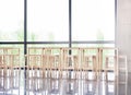 Many empty wooden stools near a table in a corporate lobby area, luch room, calm business canteen, no people, nobody. Vacant seats