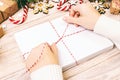 Many envelopes tied with rope. Close-up top view of famale hands with envelope. Pine cones and christmas decoration on