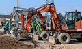 Many excavators of different colors and sizes lined up at the construction site, waiting to get back to work Royalty Free Stock Photo
