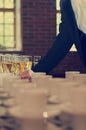 Many filled champagne glasses in rows, person taking one wine glass. Blurry coffee cups in the foreground. Elegant and luxurious Royalty Free Stock Photo