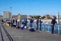 Many fisherman along the rail fence on one side of a long pier fishing in the ocean