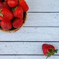 Many fresh red strawberries in woden bowl and one berry top view. Strawberry fruits on white old table copy space Royalty Free Stock Photo