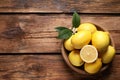 Many fresh ripe lemons with green leaves and flower on wooden table, top view. Space for text Royalty Free Stock Photo