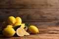 Many fresh ripe lemons with green leaves on wooden table, space for text Royalty Free Stock Photo