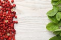 Many fresh wild strawberries, flowers and leaves on white wooden table, flat lay. Space for text Royalty Free Stock Photo