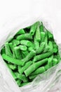 Many frozen bright green beans pods in a package, vertical frame