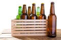 Many glass bottles of different beer on wooden box with no label isolated, Photo of different full beer bottles with no labels.