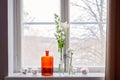 Many glass vases and jugs and flowers on a windowsill. Clear glass vases and one orange glass vase with different white flowers Royalty Free Stock Photo