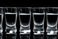 Many glasses of vodka isolated on black background