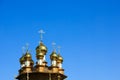 Golden domes of wooden church on bright blue sky background Royalty Free Stock Photo