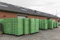 Many green fish boxes are stacked outside the fishing auction at the harbor