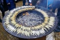 Many grilled smelt on a large round flat grill with open fire hole in the center, seafood cooking Royalty Free Stock Photo