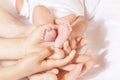 Many hands adult, child hold newborn infant feet