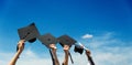 Many hands holding graduation hats