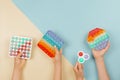 Many hands holding trendy pop it fidget toys on background. Push pop-it fidgeting game helps relieve stress, anxiety