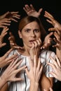 Many hands stretched to woman on dark background. Panic attack Royalty Free Stock Photo