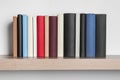 Many hardcover books on wooden shelf near white wall