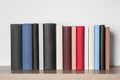 Many hardcover books on wooden table near white wall