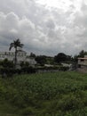 Many havey range of clouds on sky , some fields and trees in house near fields.