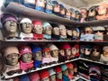 Many heads of mannequins are on the shelves dressed in colorful hats and glasses Royalty Free Stock Photo