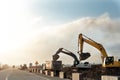 Many heavy heavy industrial road construction machinery on new highway road construction site sunny day with blue sky background. Royalty Free Stock Photo