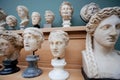 Many human faces and marble heads copies of old Roman gods and emperors on shelf. Memories about human of ancient world