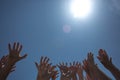 Many human Hands reach out to the sun against the backdrop of a bright blue sky Royalty Free Stock Photo