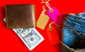 Many hundreds of dollars banknotes in a leather wallet with colored cardboard tags, price tags on a red background. Flat lay.