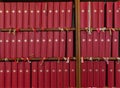 Many identical red books with bookmarks on the shelf