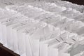 Many identical white cardboard paper gift bags