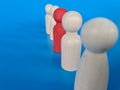 Many identical wooden men standing side by side and one person is figurine of unique red color Royalty Free Stock Photo