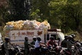 Many indian motorcyclists and truck with pile of colorful bags